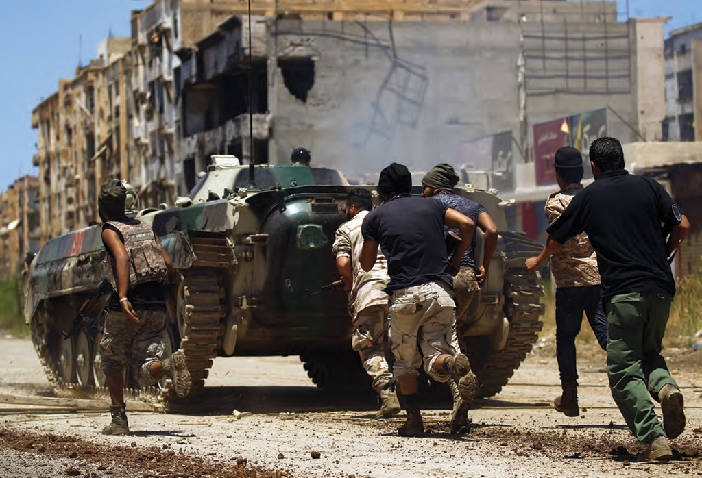 Members of the forces loyal to Khalifa Haftar, take cover behind an armored vehicle during clashes in the destroyed city of Benghazi. AFP PHOTO / ABDULLAH DOMA