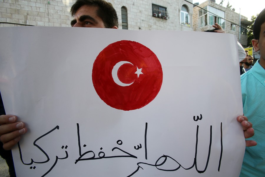 People supporting the legitimate government of Turkey gathered in front of the Turkish Embassy in Amman, Jordan. A demonstrator carries a placard with the Turkish flag and the words “God bless Turkey.”  AA PHOTO /  SALAH MALKAWI