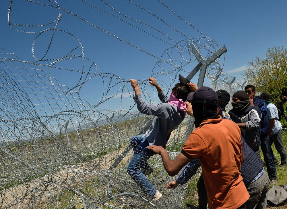 Migrants and refugees try to break down the border fence between Greece and Macedonia at the makeshift camp near the village of Idomeni, on April 16, 2016. AFP PHOTO / DANIEL MIHAILESCU