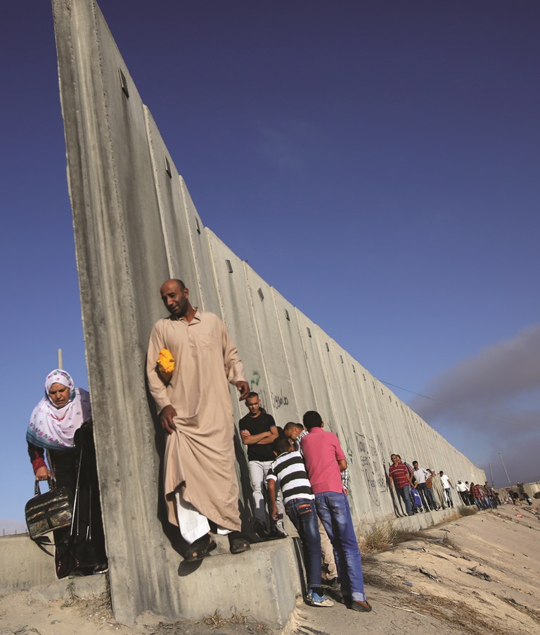Palestinians walk along part of Israel’s controversial separation barrier while they cross from the West Bank to Jerusalem for Friday prayers at the Al-Aqsa Mosque, as Israel has limited access to the mosque.  AFP PHOTO / ABBAS MOMANI