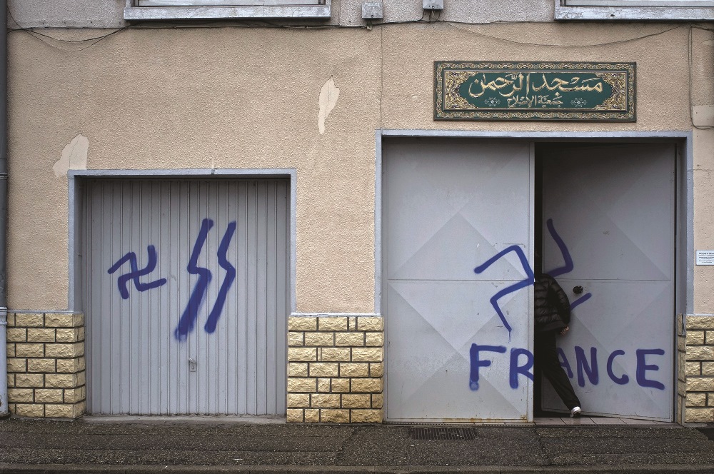 A worshiper opens the door of a mosque where nazi graffiti had been sprayed, on December 20, 2011 in Décines, a neighboring suburb of the French southeastern city of Lyon. AFP / Jean-Philippe Ksiazek